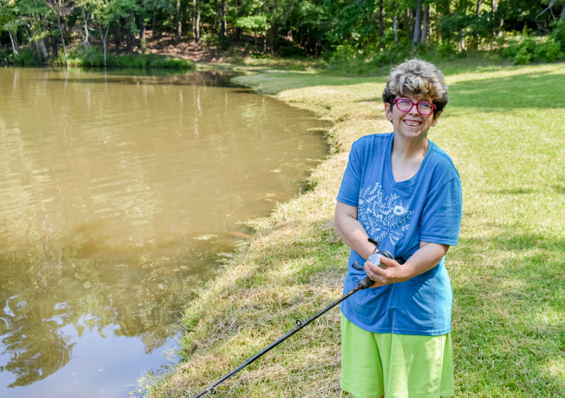 a person holding a fishing pole by a body of water